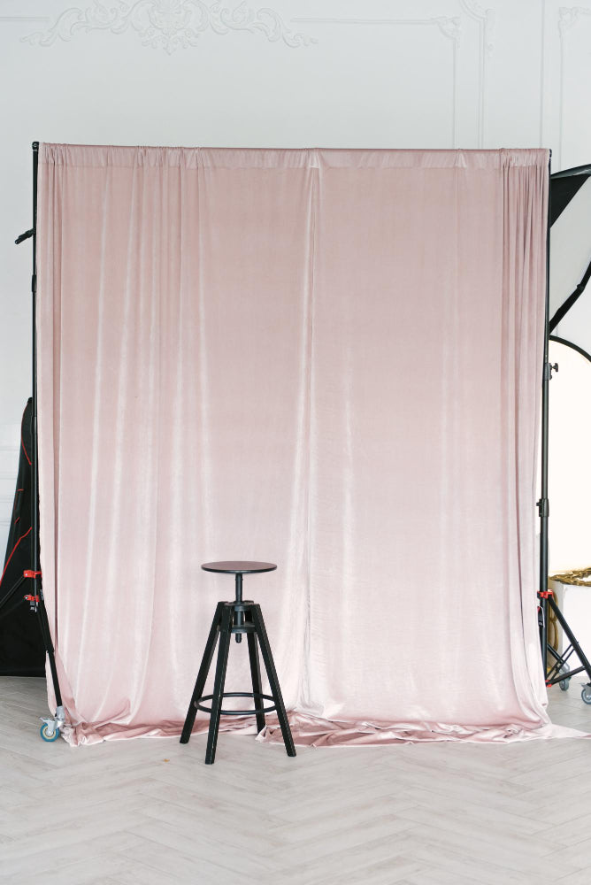 Pink backdrop with a black stool in front of a white wall